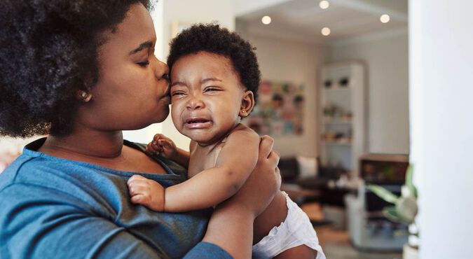 Mãe confortando bebê chorando no colo.