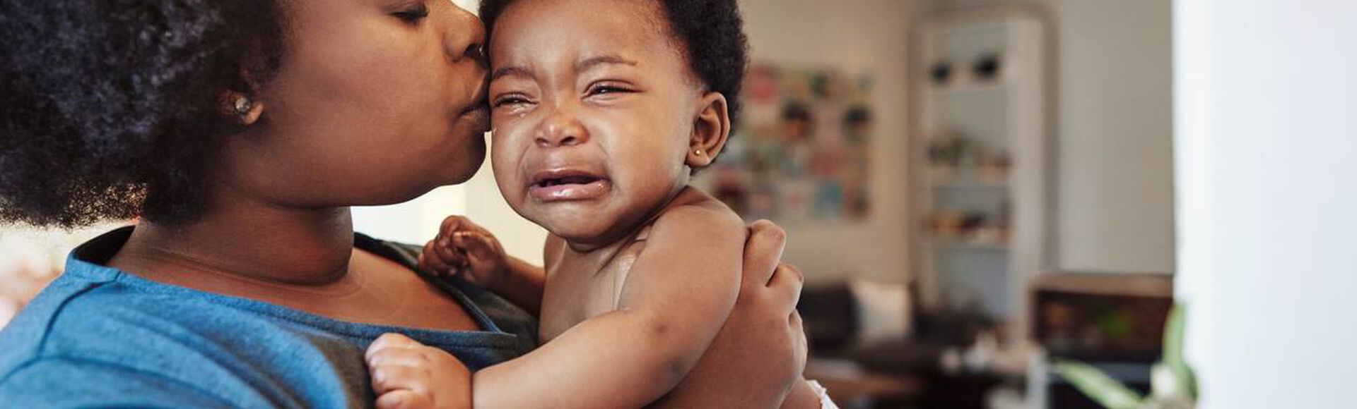 Mãe confortando bebê chorando no colo.