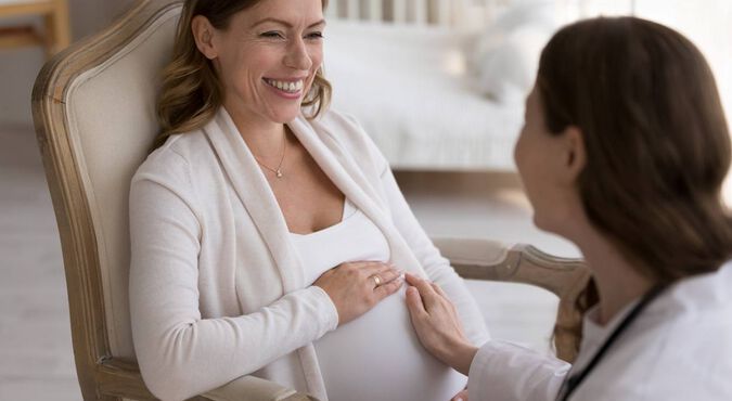 Mulher grávida sorrindo durante consulta médica