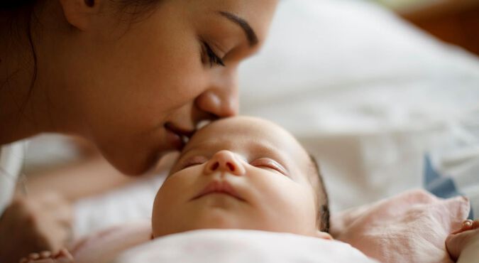Mãe cheirando testa de seu bebê