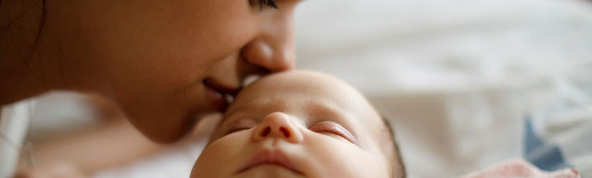 Mãe cheirando testa de seu bebê