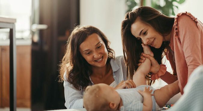 Duas mães interagindo com um bebê em casa