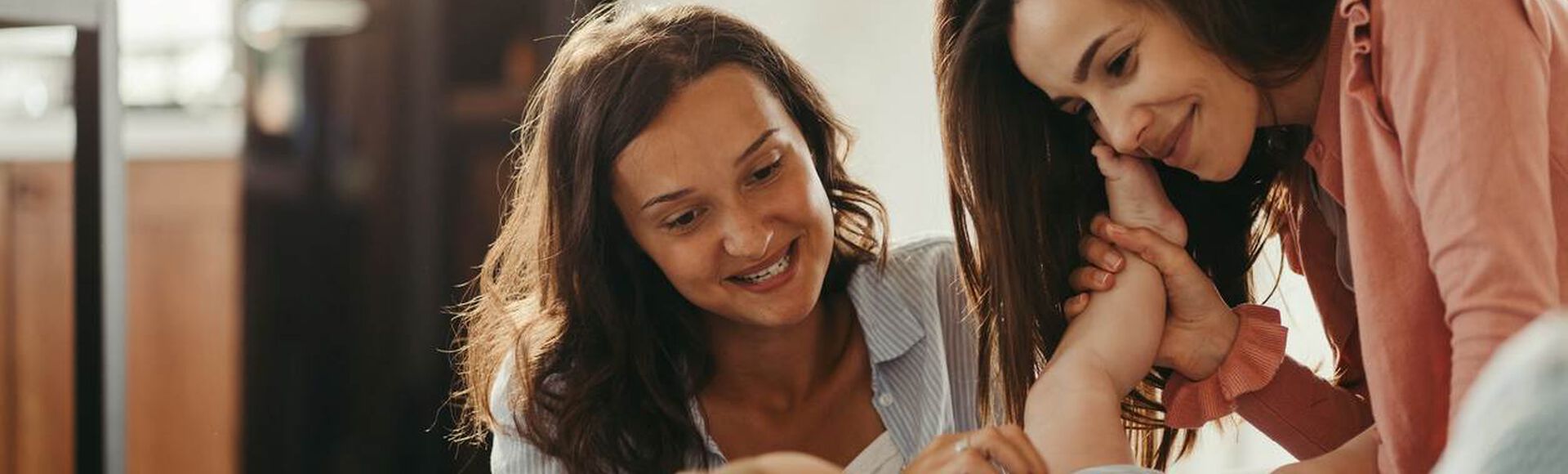 Duas mães interagindo com um bebê em casa