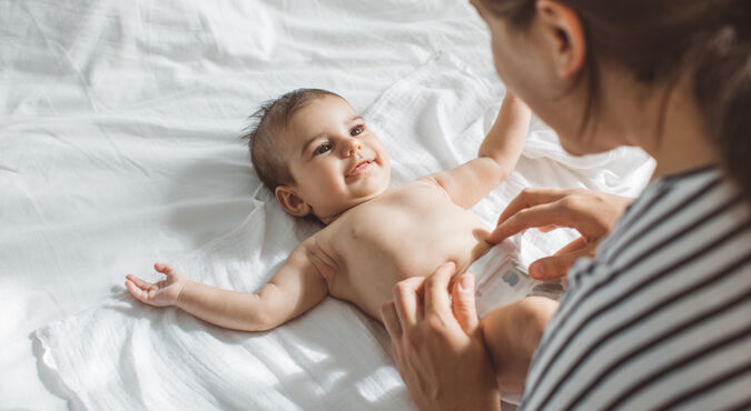 Cuidador trocando fralda de bebê com atenção e delicadeza