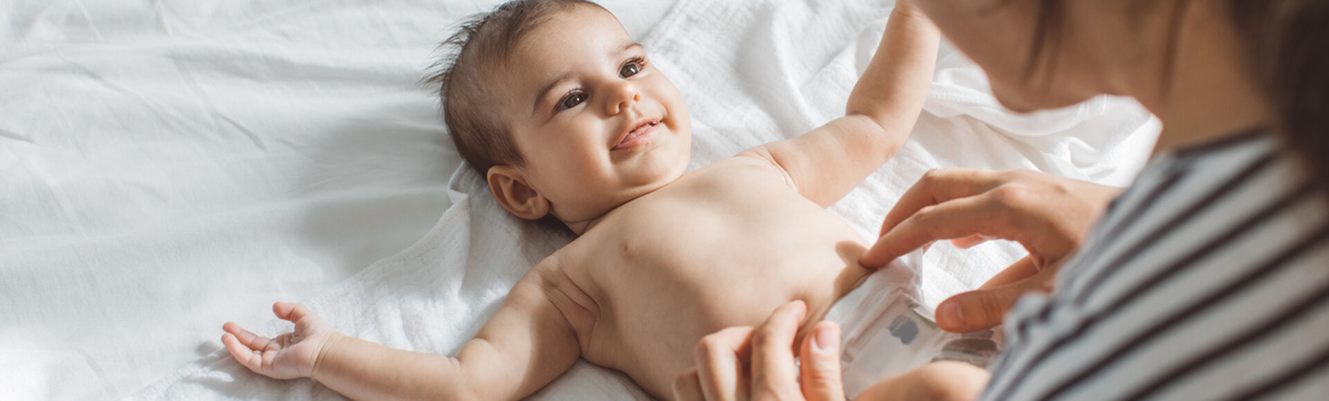 Cuidador trocando fralda de bebê com atenção e delicadeza