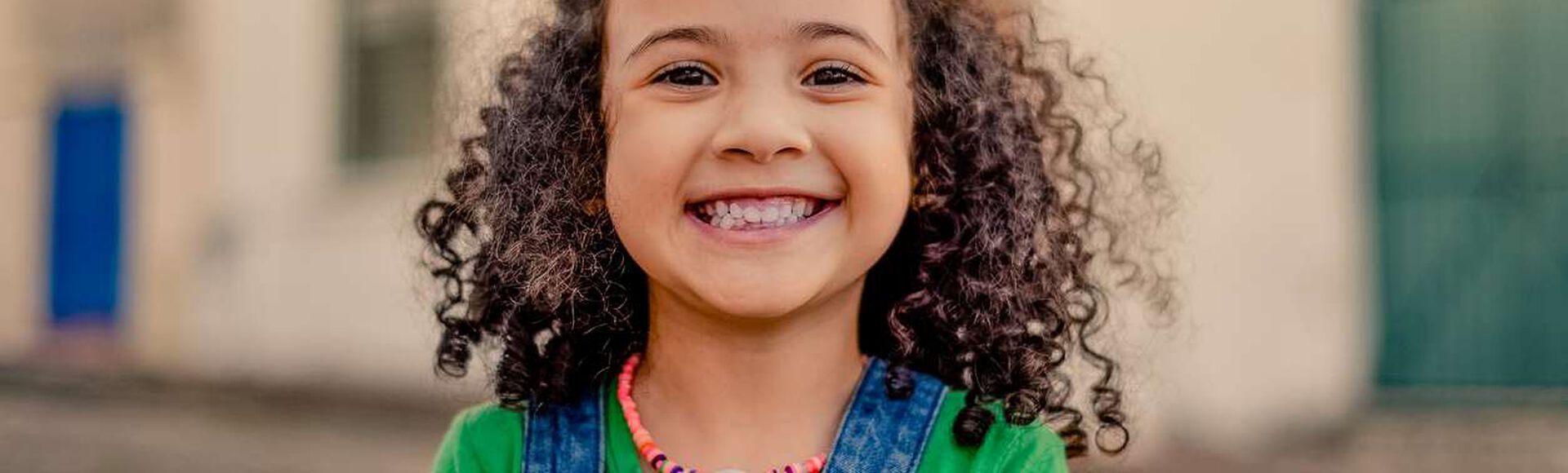 Linda e sorridente menininha com seus cachos bem cuidados.
