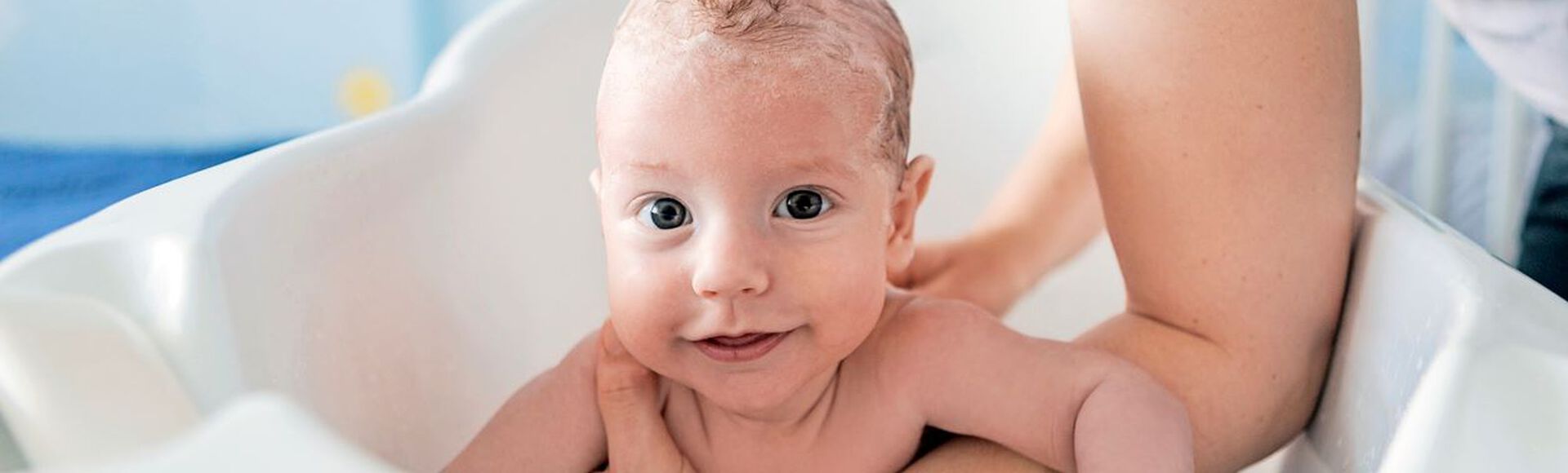 Bebê sorridente tomando banho com o cabelo ensaboado