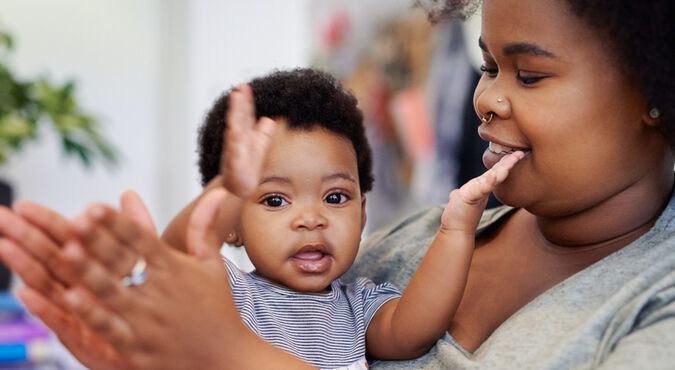 Bebê batendo palmas no colo da mãe