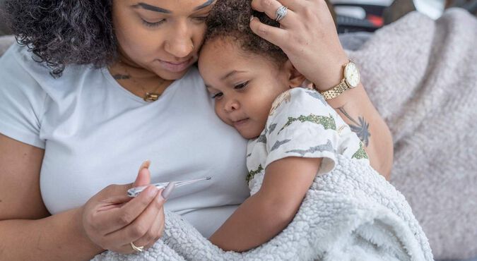 Mãe segurando bebê gripado enrolado em cobertor