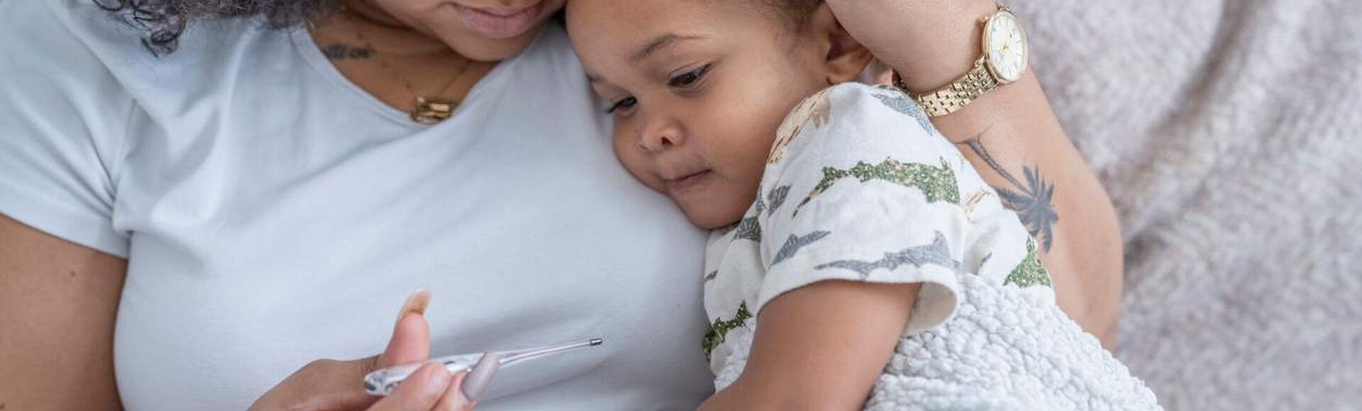 Mãe segurando bebê gripado enrolado em cobertor