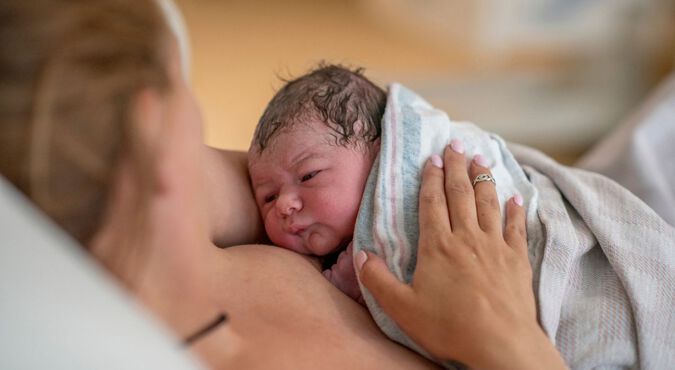 Gestante no pós-parto segurando seu bebê recém-nascido