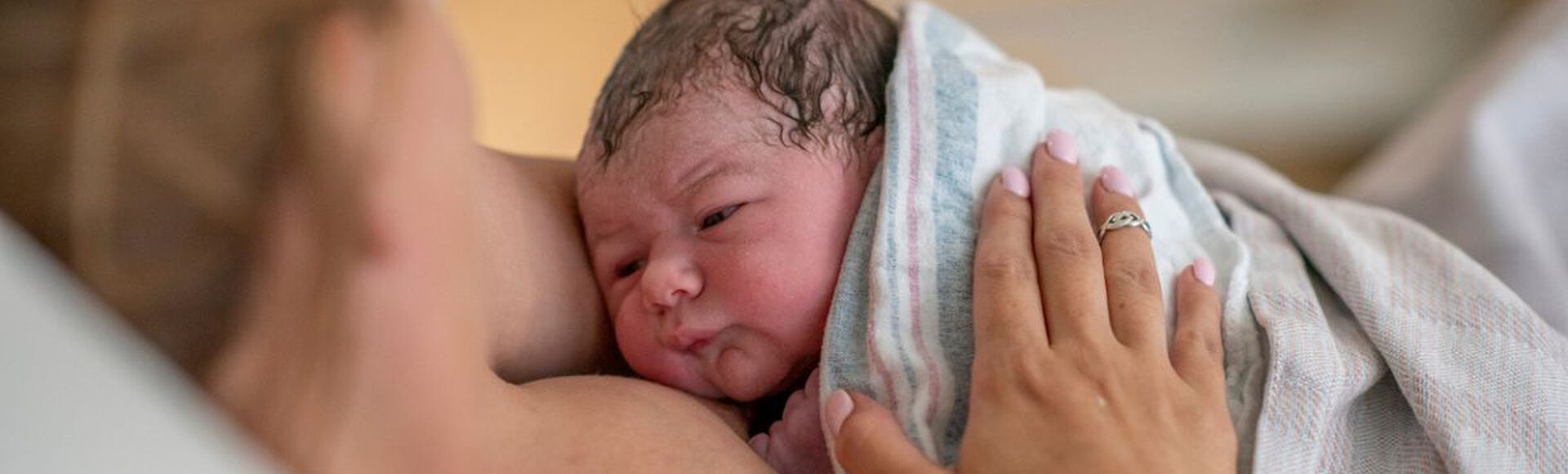 Gestante no pós-parto segurando seu bebê recém-nascido