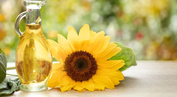 Frasco de óleo de girassol ao lado de uma flor de girassol