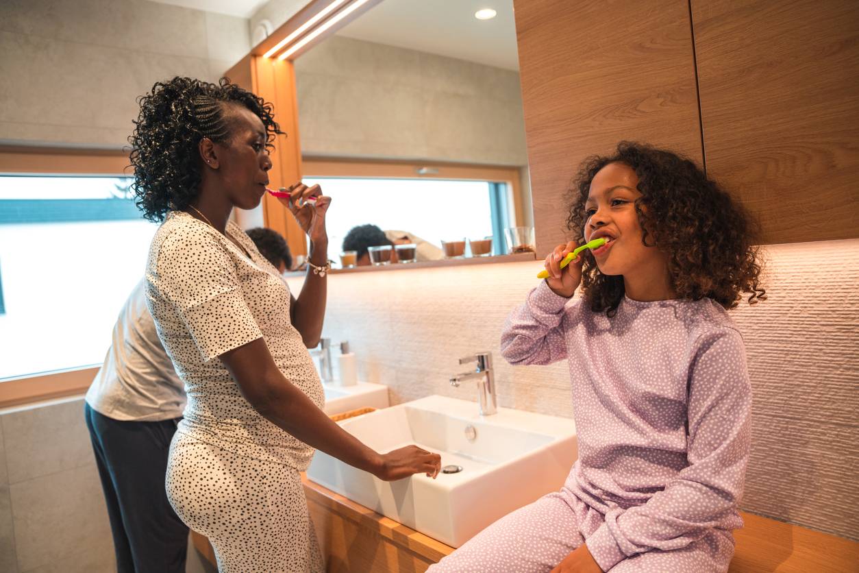 Mulher negra gestante com a mão na boca indicando dor de dente na gravidez|Seus Abraços Inspiram os Nossos Huggies® Brasil