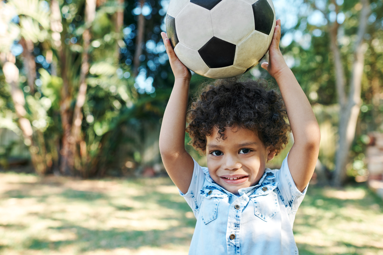 Menino brincando com uma bola, que é uma atividade para o desenvolvimento da educação infantil|Seus Abraços Inspiram os Nossos Huggies® Brasil