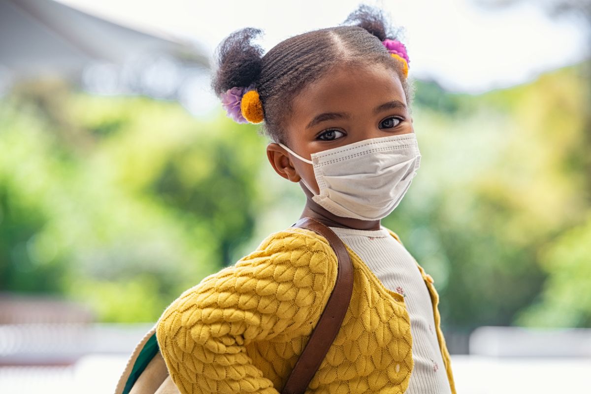 Menina negra usando máscara orofacial e posando para câmera.