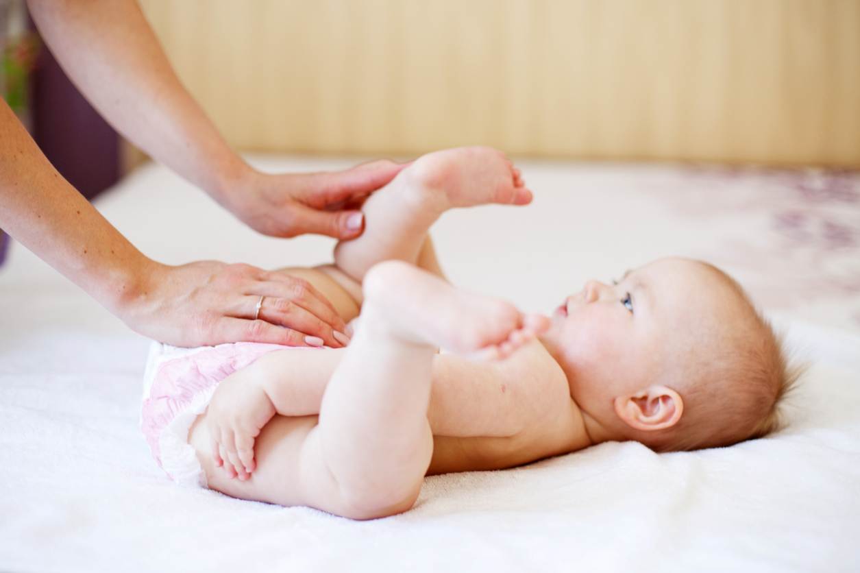 Bebê, com perninhas para o ar, fralda recém trocada, olhando para sua mamãe.