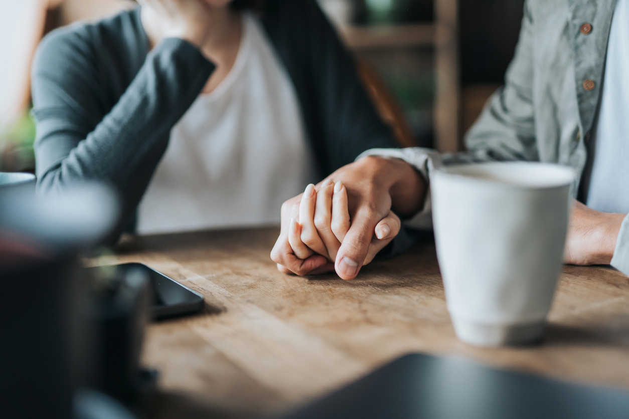 Casal de mãos dadas apoiadas sobre uma mesa 