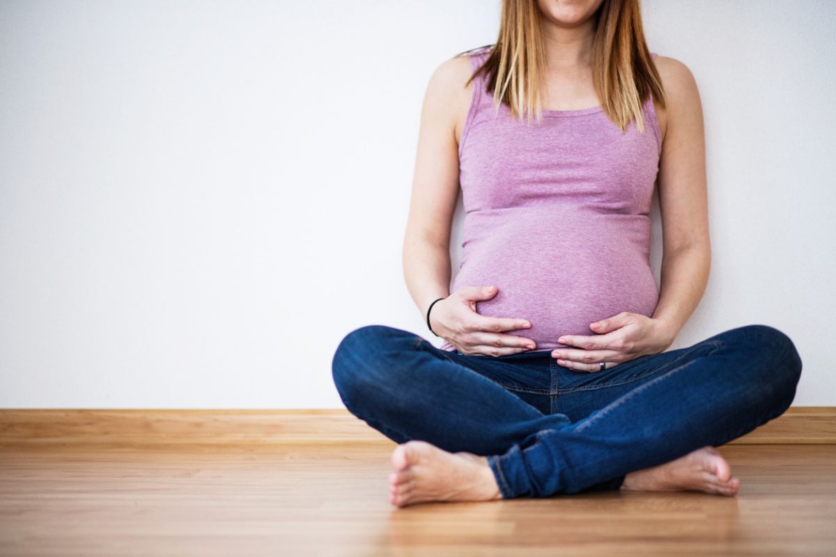 Gestante sentada em sofá com calendário nas mãos