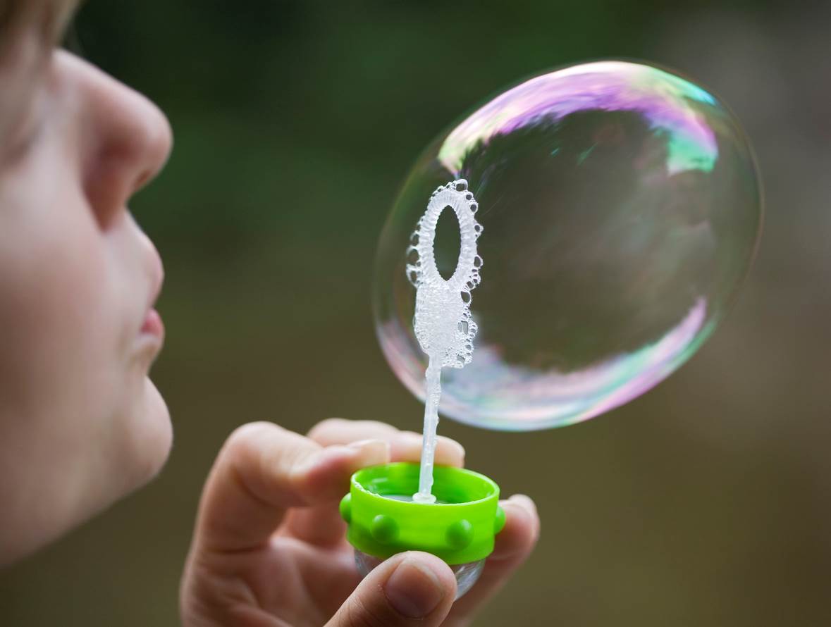 criança soprando uma bolha de sabão grande 