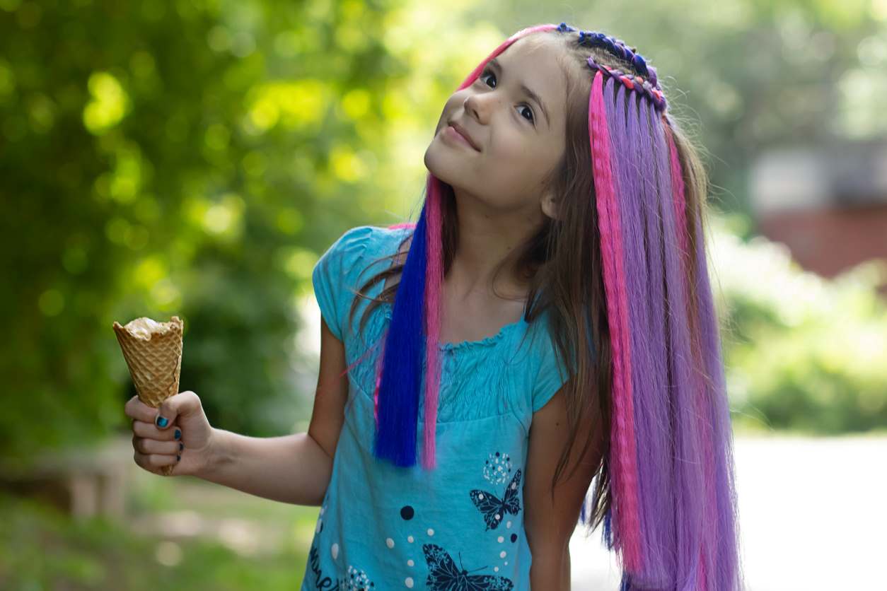 Menina com penteado infantil colorido segurando um sorvete.