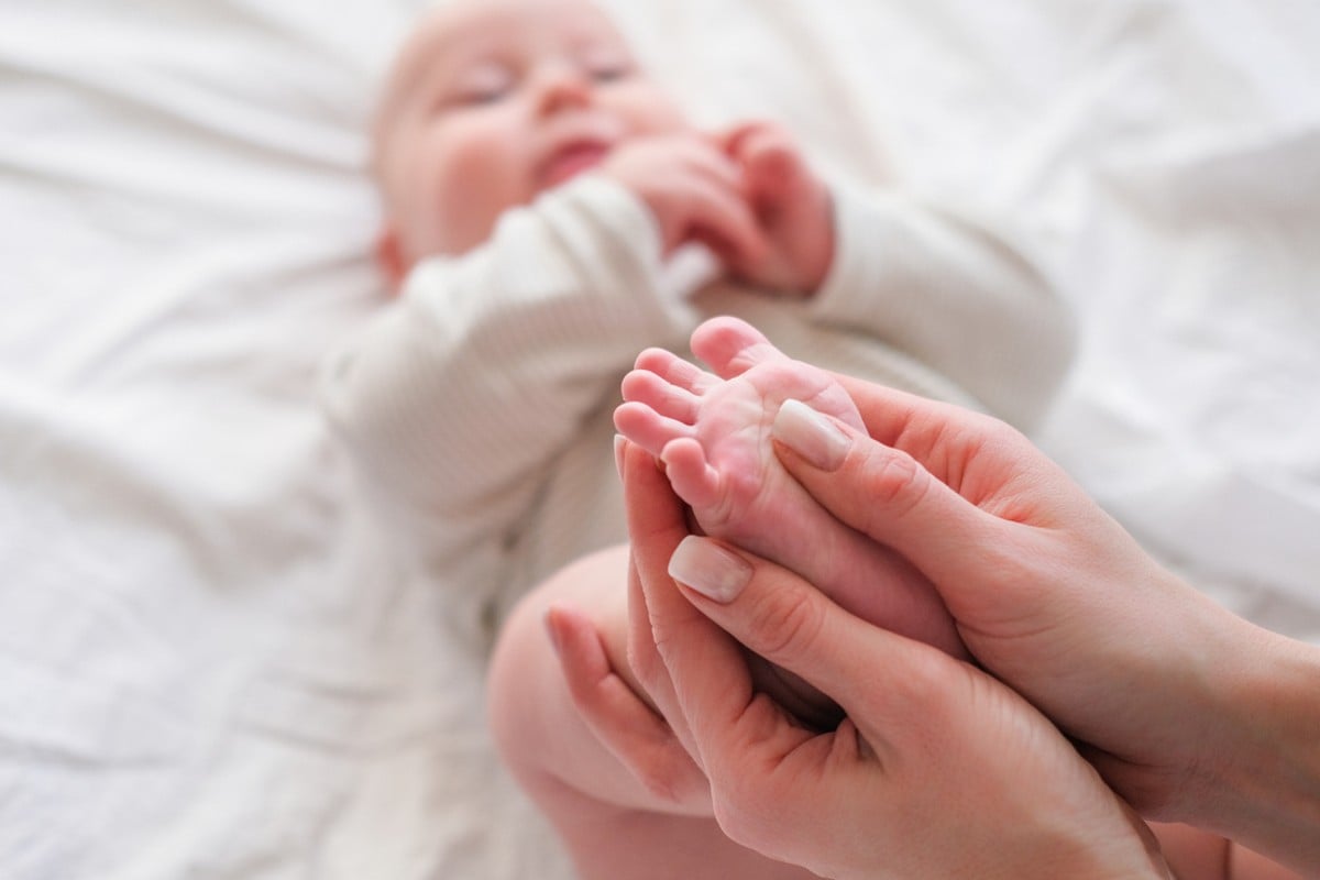 Cuidador fazendo massagem no pe do bebe