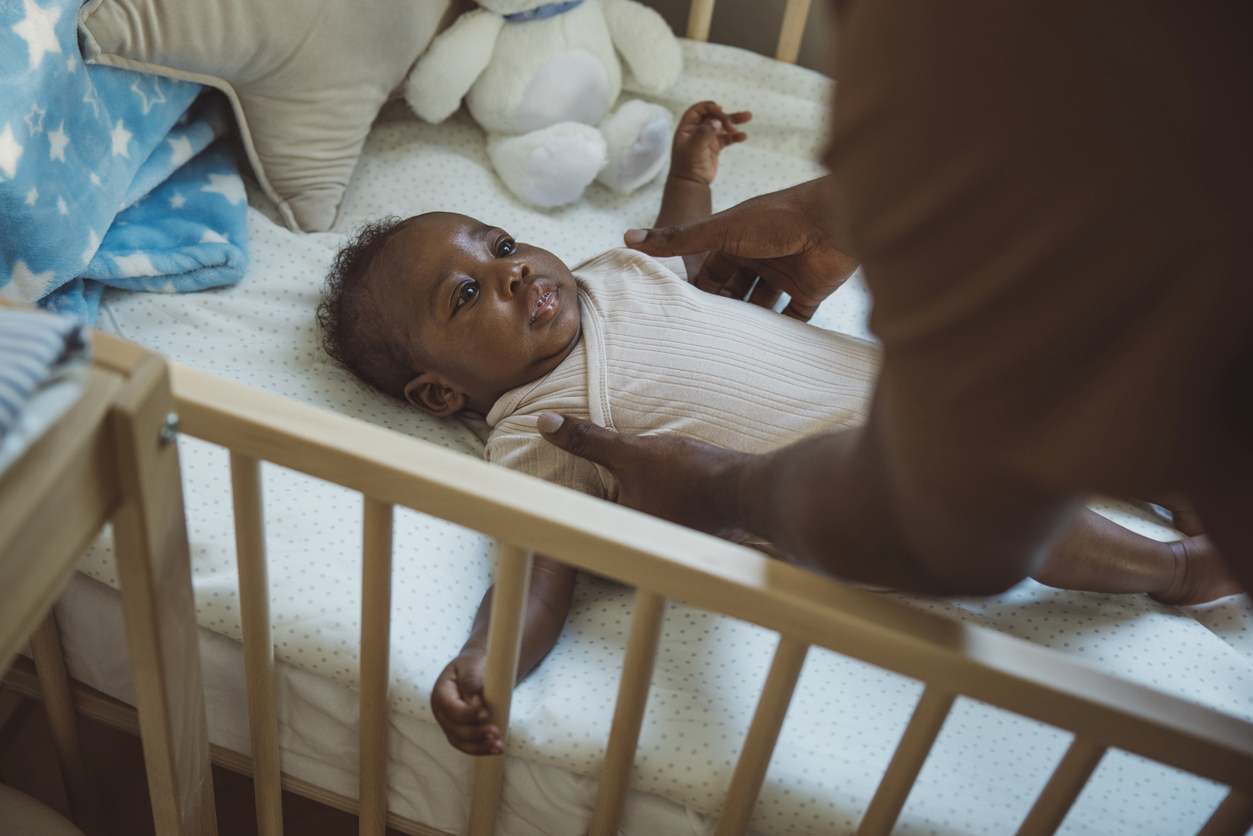 Pai pegando seu bebê do bercinho durante a noite.