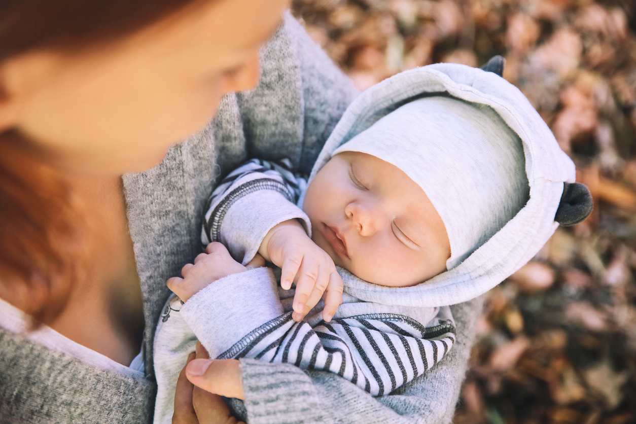 Bebê dormindo no colo com roupa de inverno